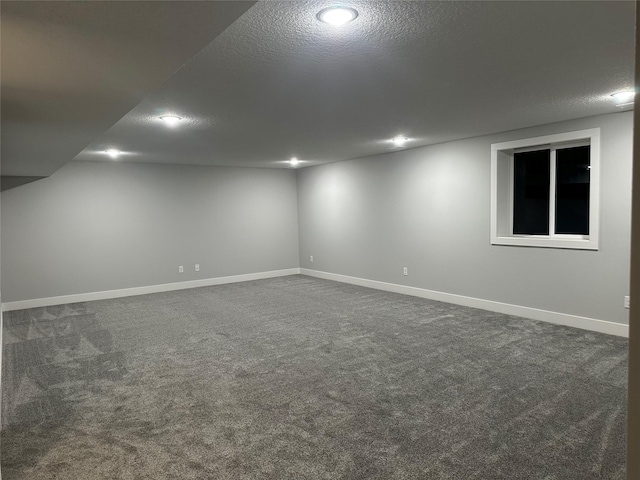 basement featuring a textured ceiling and dark colored carpet