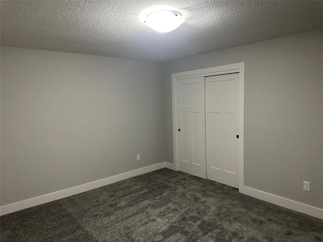 unfurnished bedroom featuring dark colored carpet, a textured ceiling, and a closet