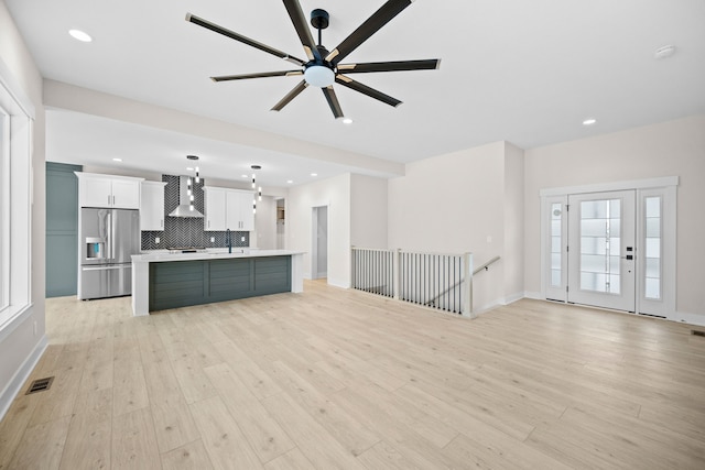 unfurnished living room featuring ceiling fan, light wood-type flooring, and sink