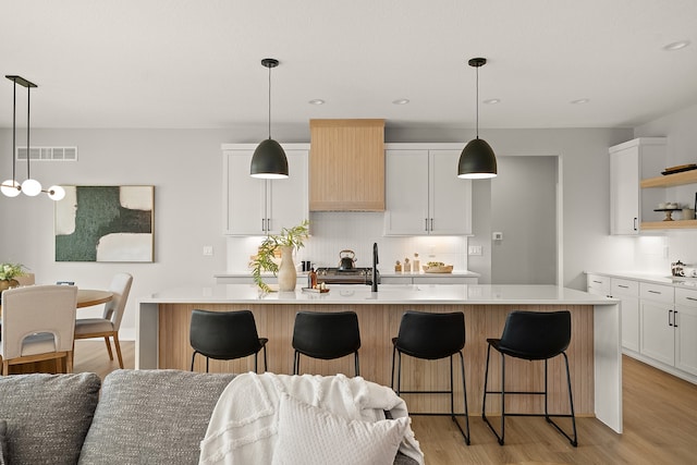 kitchen featuring white cabinetry, light hardwood / wood-style flooring, and an island with sink