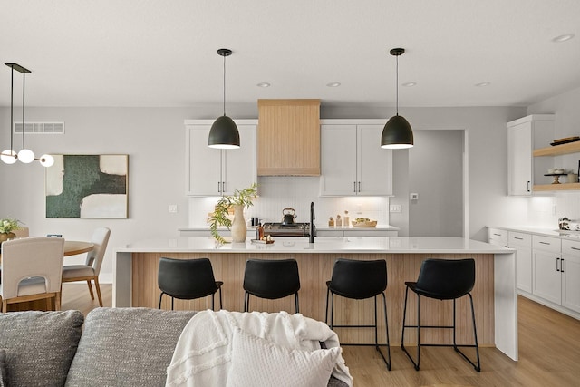 kitchen featuring open shelves, light wood-style floors, visible vents, and light countertops