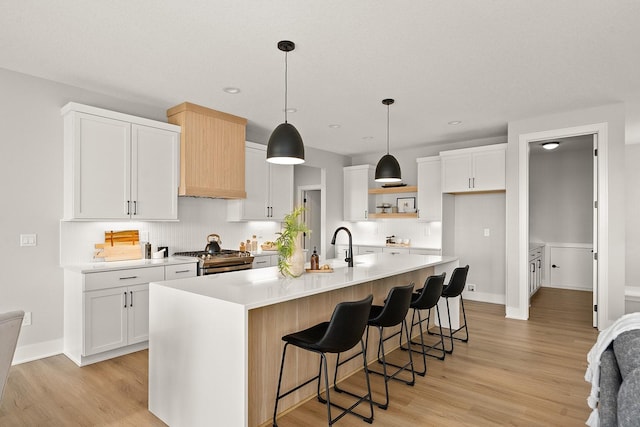 kitchen featuring high end range, white cabinetry, light countertops, and light wood-type flooring