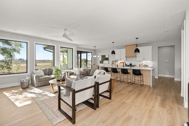 living room featuring ceiling fan, light hardwood / wood-style floors, and sink