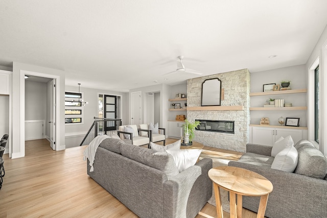 living room with ceiling fan, light wood-type flooring, and a fireplace