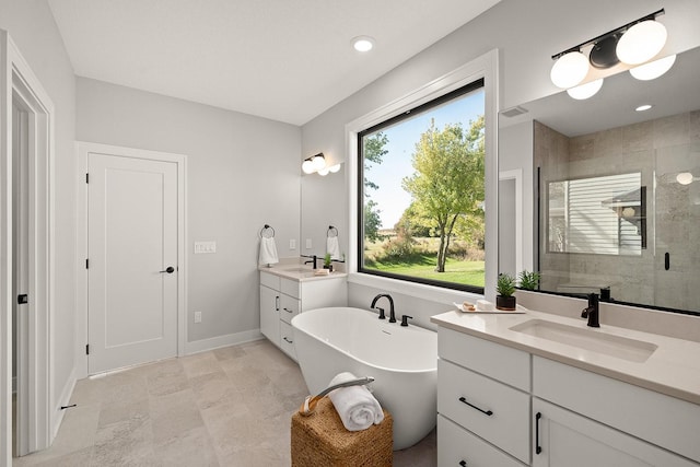 bathroom with a shower stall, two vanities, a soaking tub, and a sink