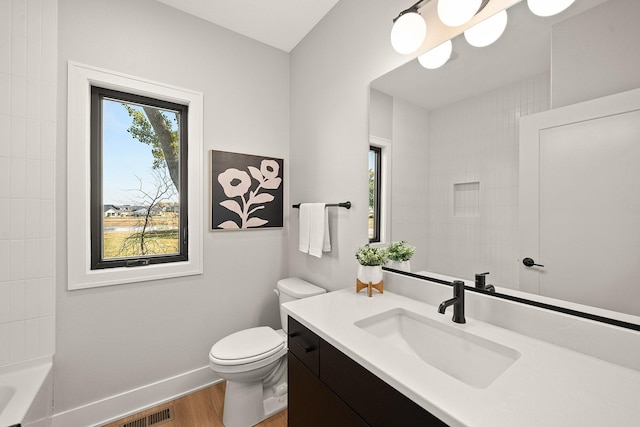 bathroom with wood finished floors, vanity, baseboards, toilet, and visible vents