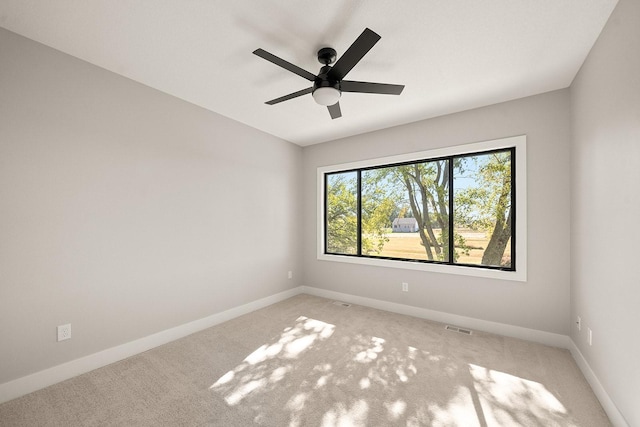 spare room with light carpet, a ceiling fan, visible vents, and baseboards