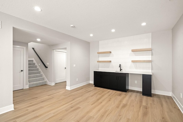 bar with a sink, recessed lighting, backsplash, light wood-style floors, and stairs
