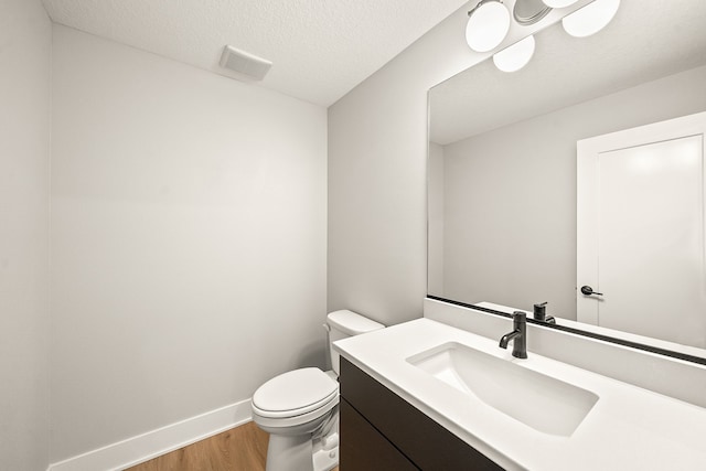 bathroom with wood-type flooring, vanity, a textured ceiling, and toilet