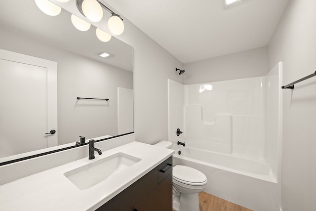 full bathroom featuring hardwood / wood-style flooring, vanity,  shower combination, and toilet