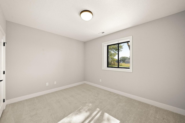 carpeted empty room featuring baseboards and visible vents