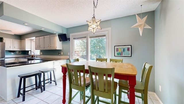 dining space with a textured ceiling, light tile patterned floors, and baseboards