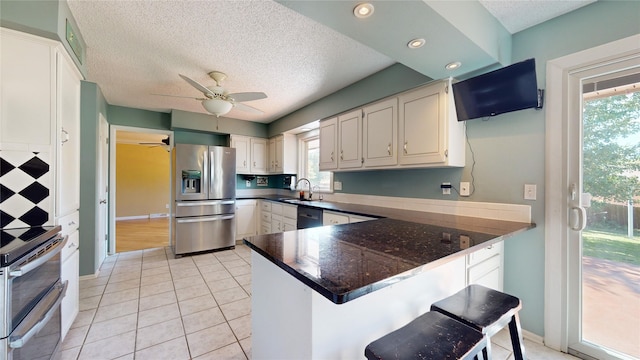 kitchen with a peninsula, dark countertops, a healthy amount of sunlight, and appliances with stainless steel finishes