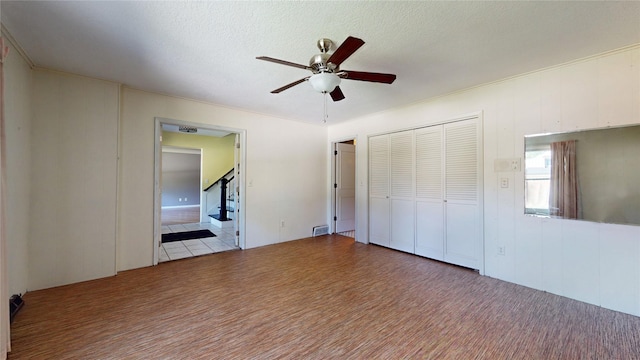 unfurnished bedroom with ceiling fan, a closet, wood finished floors, and a textured ceiling