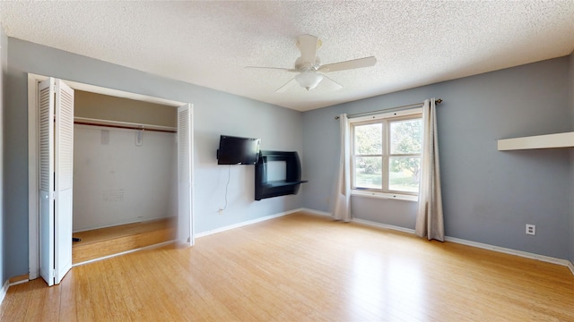 unfurnished bedroom featuring a closet, ceiling fan, a textured ceiling, and wood finished floors