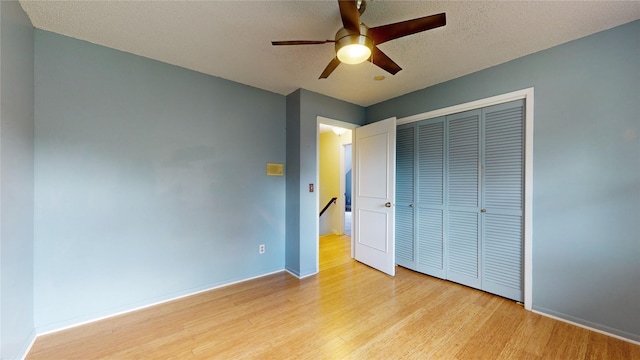 unfurnished bedroom with baseboards, light wood-style flooring, ceiling fan, a textured ceiling, and a closet