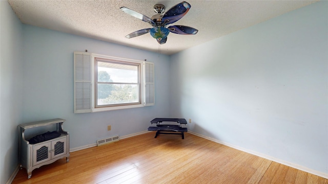 unfurnished room with visible vents, a ceiling fan, a textured ceiling, baseboards, and hardwood / wood-style flooring