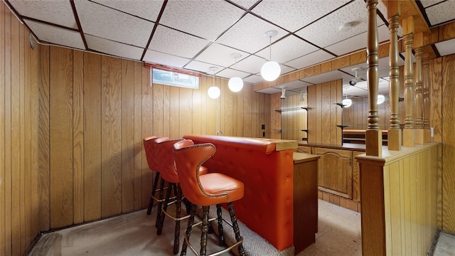 bar with a dry bar, wood walls, and a drop ceiling