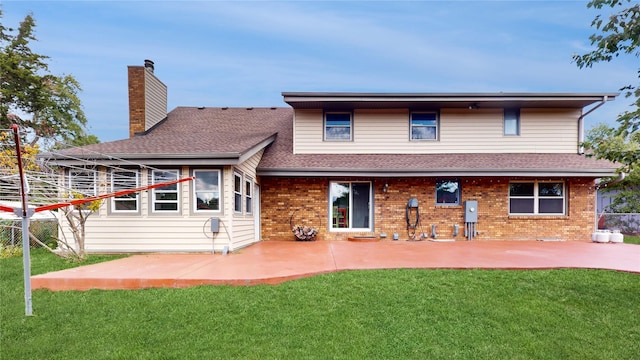 rear view of property featuring a yard, brick siding, a patio, and a chimney