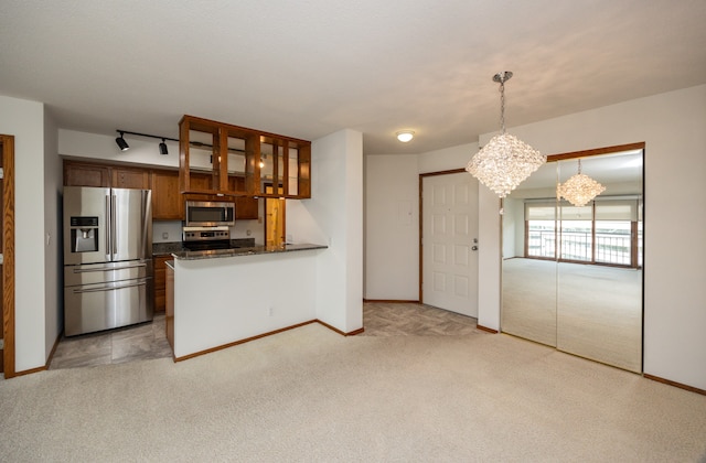 kitchen with light colored carpet, stainless steel appliances, an inviting chandelier, and kitchen peninsula