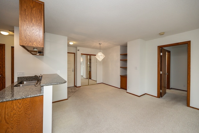 kitchen featuring decorative light fixtures, sink, and light colored carpet