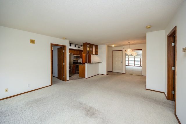 unfurnished living room featuring light carpet, a textured ceiling, and a notable chandelier