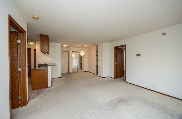 unfurnished living room featuring a textured ceiling and light colored carpet