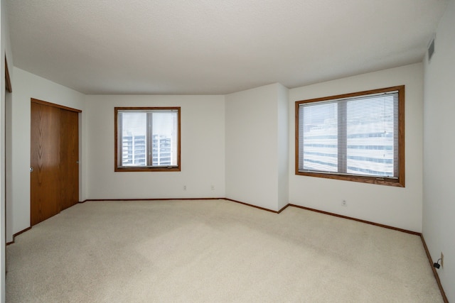 carpeted spare room featuring a textured ceiling and a wealth of natural light