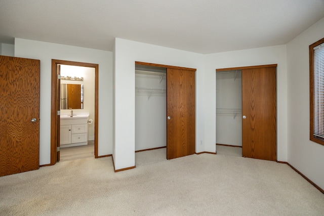 carpeted bedroom featuring ensuite bath, two closets, and sink