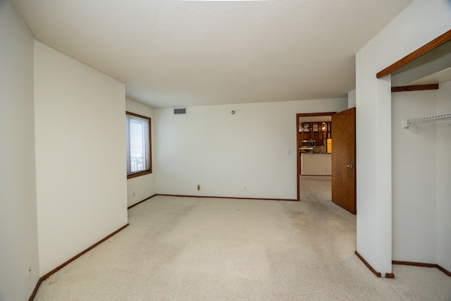 interior space with a textured ceiling and light carpet