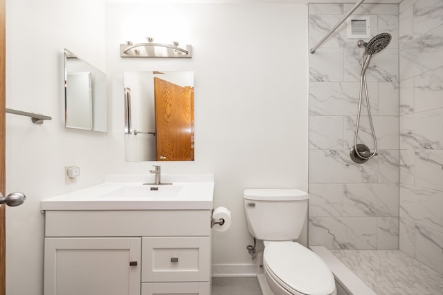 bathroom featuring vanity, toilet, and a tile shower