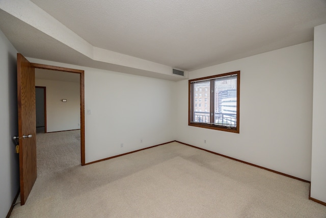 spare room with a textured ceiling and light colored carpet