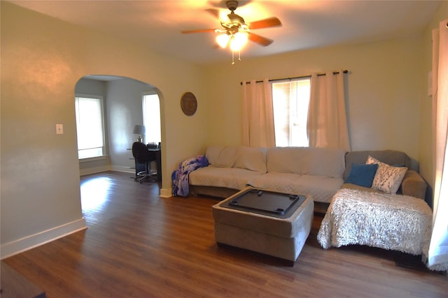 living room with baseboards, arched walkways, dark wood finished floors, and a ceiling fan