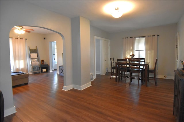 dining area featuring ceiling fan, wood finished floors, arched walkways, and baseboards