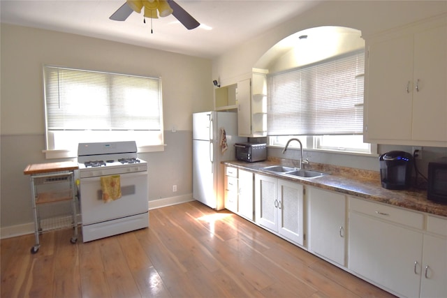 kitchen featuring light wood-type flooring, white cabinets, white appliances, a ceiling fan, and a sink