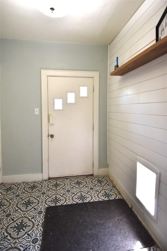 doorway to outside featuring baseboards and wooden walls