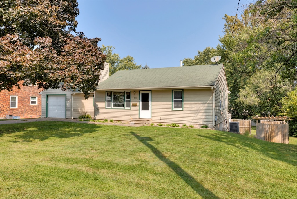 ranch-style home with a garage, a front yard, and central air condition unit