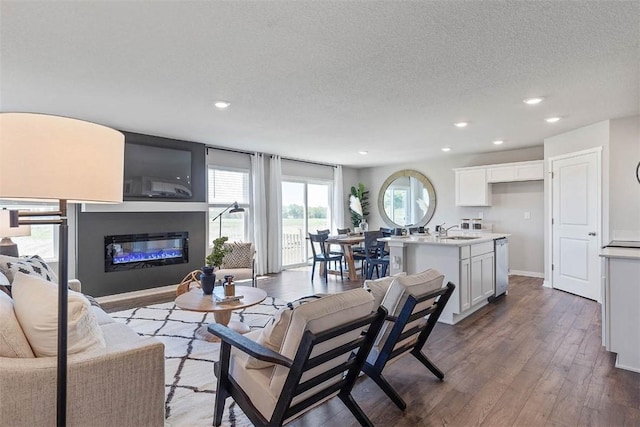 living room with baseboards, recessed lighting, wood finished floors, a glass covered fireplace, and a textured ceiling