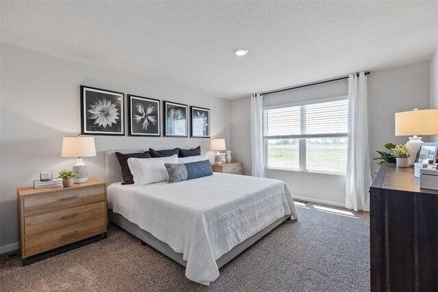 bedroom with a textured ceiling and dark colored carpet