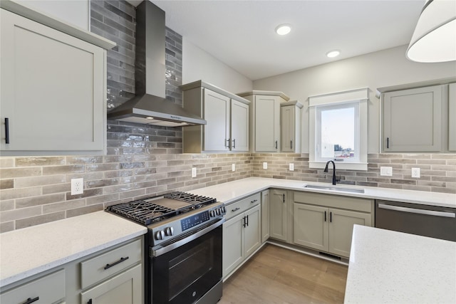 kitchen with wall chimney exhaust hood, sink, appliances with stainless steel finishes, and tasteful backsplash