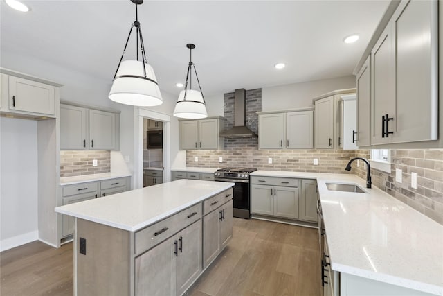 kitchen featuring pendant lighting, wall chimney range hood, sink, stainless steel range, and a kitchen island