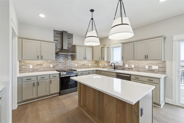 kitchen with sink, a center island, wall chimney exhaust hood, pendant lighting, and appliances with stainless steel finishes