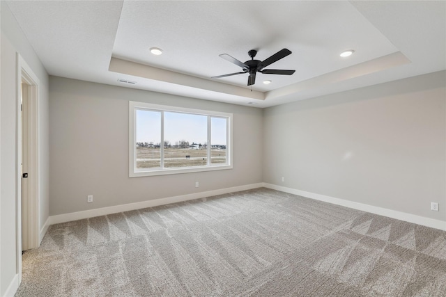 carpeted empty room with a tray ceiling and ceiling fan