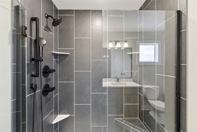 bathroom with a tile shower, vanity, and toilet