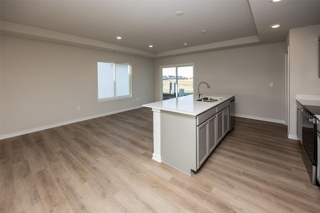 kitchen featuring sink, range with electric cooktop, an island with sink, and light wood-type flooring