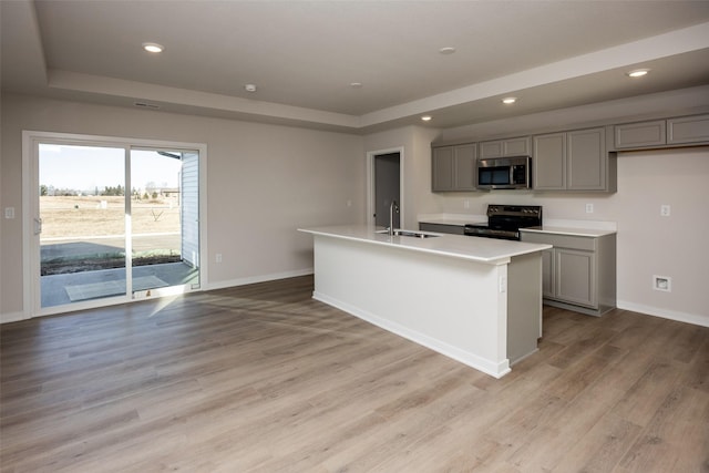 kitchen with gray cabinets, black electric range oven, sink, and a center island with sink