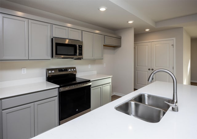 kitchen featuring appliances with stainless steel finishes, sink, wood-type flooring, and gray cabinetry