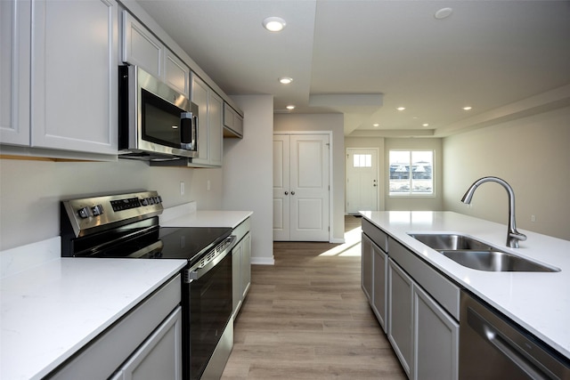 kitchen featuring stainless steel appliances, sink, gray cabinetry, and light hardwood / wood-style floors