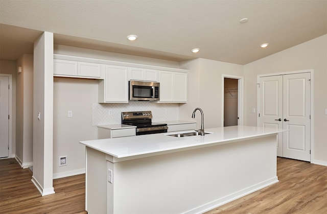 kitchen featuring white cabinets, decorative backsplash, a kitchen island with sink, and stainless steel appliances