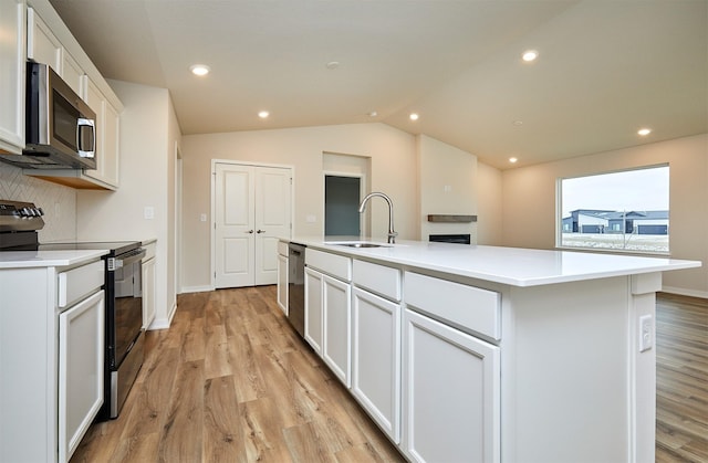 kitchen featuring appliances with stainless steel finishes, backsplash, a kitchen island with sink, sink, and white cabinetry